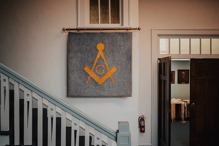 Emblema de escuadra y compás dorado colgado en el muro de un templo masónico
