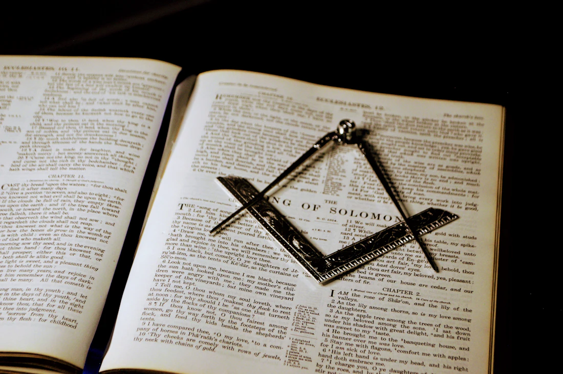 Escuadra y compás de plata sobre un libro abierto, símbolos esenciales de la masonería